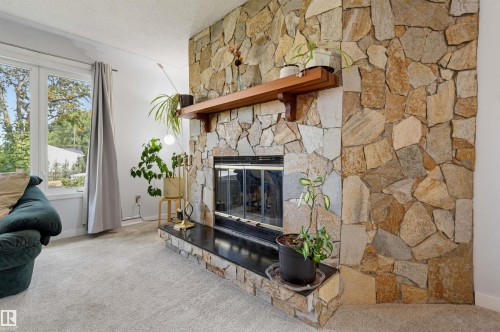 Stone-clad fireplace with a wood mantel, raised hearth, and carpeted flooring - 13655 122 Avenue Nw, Edmonton, AB 