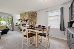 Stone-clad fireplace with wood mantle, large bay window, neutral carpeting, and built-in cabinetry - 
