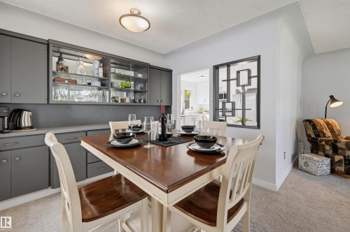 Built-in cabinetry with glass-front display, overhead flush-mount lighting, and an open pass-through window to an additional space - 13655 122 Avenue Nw, Edmonton, AB 