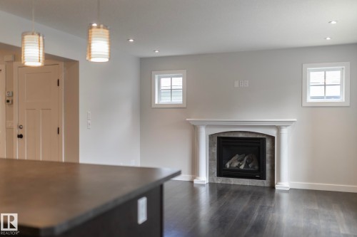 Wood-finish flooring, recessed lighting, and a white mantel fireplace with a dark tile surround - 53 Michigan Street, Devon, AB 