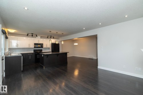 Kitchen featuring dark wood-finish flooring, a kitchen island, white upper cabinetry, dark lower cabinetry, and recessed lighting - 53 Michigan Street, Devon, AB 