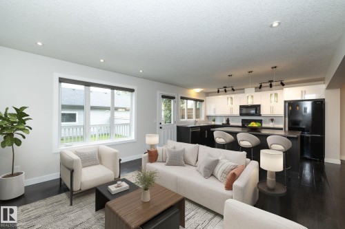 Open-concept living space featuring dark wood-finish flooring, recessed lighting, and a modern kitchen with a large island - 53 Michigan Street, Devon, AB 