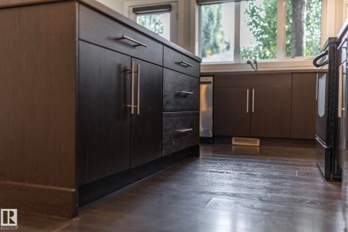 Dark wood-finish flooring, dark cabinetry with bar pulls, and a built-in oven - 53 Michigan Street, Devon, AB 