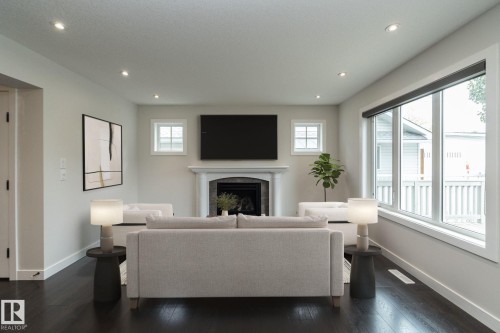 Recessed ceiling lighting, wood-finish flooring, a fireplace with a white mantel, and large windows with roller shades - 53 Michigan Street, Devon, AB 