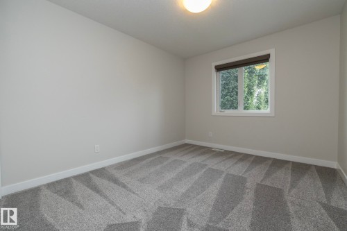 Light gray wall paint, patterned gray carpeting, white window trim, and a flush mount ceiling light fixture - 53 Michigan Street, Devon, AB 