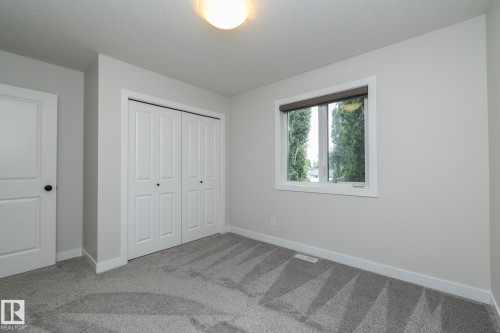 Neutral wall tones with a window featuring a roller shade, light-hued carpeting, a ceiling-mounted light fixture, and white bi-fold closet doors - 53 Michigan Street, Devon, AB 