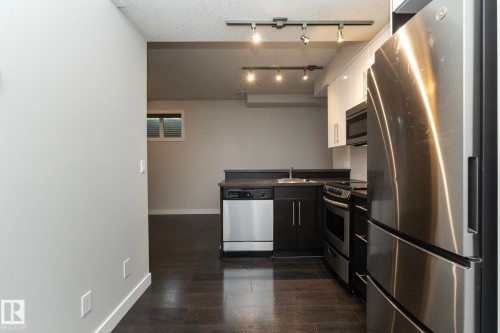 Kitchenette featuring stainless steel appliances, dark wood-finish flooring, dark countertops, white upper cabinetry, and track lighting - 53 Michigan Street, Devon, AB 