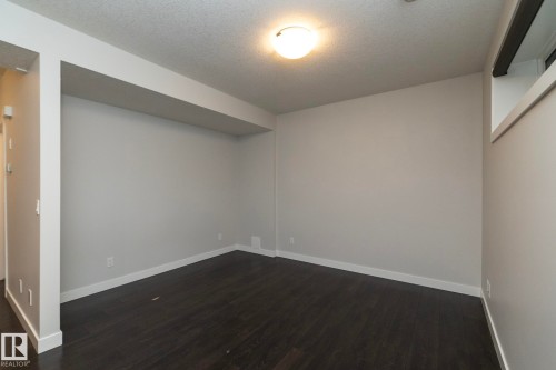 Dark wood-finish flooring with light-toned walls, featuring a recessed ceiling beam and a ceiling-mounted light fixture - 53 Michigan Street, Devon, AB 