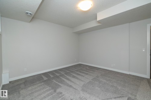 Expansive room featuring light gray walls, gray patterned carpeting, and a flush-mount ceiling light - 53 Michigan Street, Devon, AB 