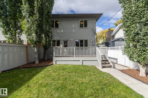 Rear exterior featuring a ground-level deck with railing, stairs, and a concrete pathway - 53 Michigan Street, Devon, AB 