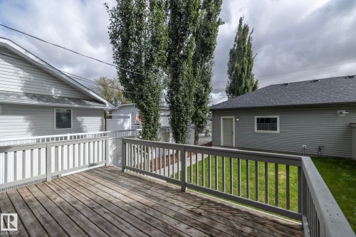 Wood-finish deck with painted railings, surrounded by green lawn and mature trees - 53 Michigan Street, Devon, AB 