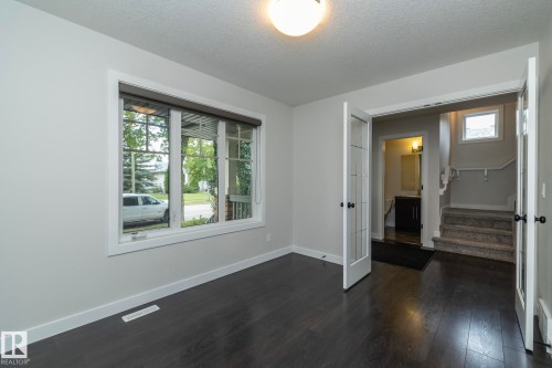 Spacious room featuring wood-finish flooring, white trim, and a large window with blinds - 53 Michigan Street, Devon, AB 