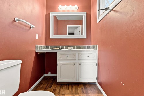 White vanity with dual cabinet storage and drawer hardware, accompanied by a tiled backsplash - 12 Hughes Road Nw, Edmonton, AB 