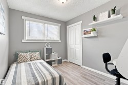 Room featuring wood-finish flooring, a double window with blinds, and a built-in bi-fold closet - 