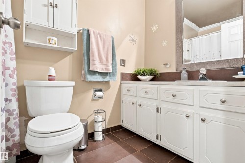 White vanity with integrated sink, coordinating wall-mounted cabinet, and brown tile flooring - 12 Hughes Road Nw, Edmonton, AB 
