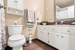 White vanity with integrated sink, coordinating wall-mounted cabinet, and brown tile flooring - 
