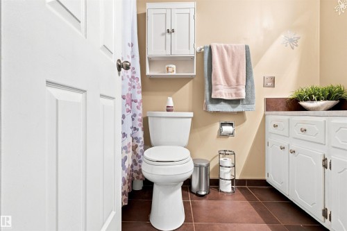 Bathroom featuring a white toilet, brown floor tiles, and a vanity with white cabinetry and a light-toned countertop - 12 Hughes Road Nw, Edmonton, AB 