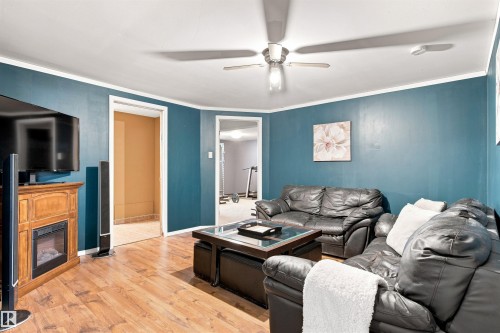 Wood-finish flooring throughout, ceiling fan, crown molding, and an integrated electric fireplace unit - 12 Hughes Road Nw, Edmonton, AB 