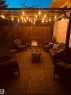 Expansive paver patio with a built-in outdoor fireplace and a wood pergola featuring string lighting - 12 Hughes Road Nw, Edmonton, AB 