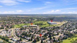 Aerial perspective showcasing a residential neighborhood with surrounding green spaces and distant commercial structures - 