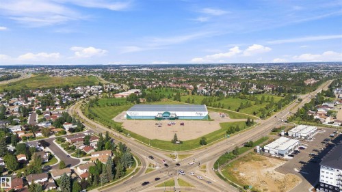 Expansive aerial showcasing a commercial structure, surrounding parkland, residential neighborhoods, and major roadways - 12 Hughes Road Nw, Edmonton, AB 