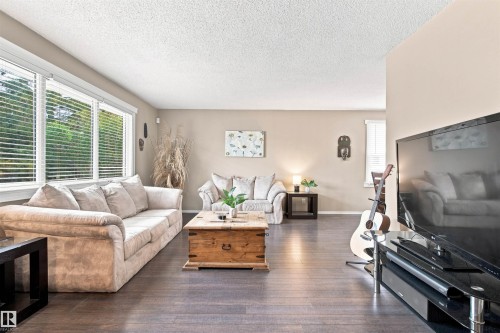 Expansive room featuring rich wood-finish flooring, multiple large windows, and neutral wall tones - 12 Hughes Road Nw, Edmonton, AB 