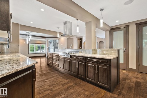 Spacious kitchen with wood-finish flooring, dark wood cabinetry, and light-toned stone countertops - 10 Eldorado Drive, St. Albert, AB 