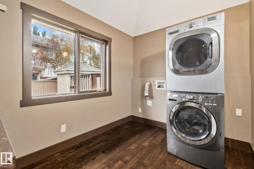 Window with dark trim, stackable washer and dryer, wood-finish flooring, and neutral wall paint - 10 Eldorado Drive, St. Albert, AB 
