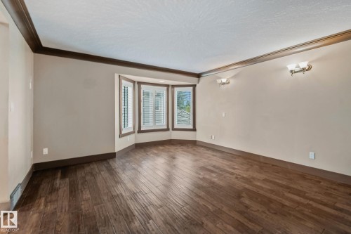 Bay window with plantation shutters, dark wood-finish flooring, sconce lighting, and crown molding - 10 Eldorado Drive, St. Albert, AB 