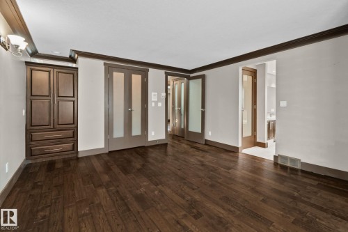 Rich wood-finish flooring, built-in cabinetry, frosted glass double doors, and coordinating trim details - 10 Eldorado Drive, St. Albert, AB 