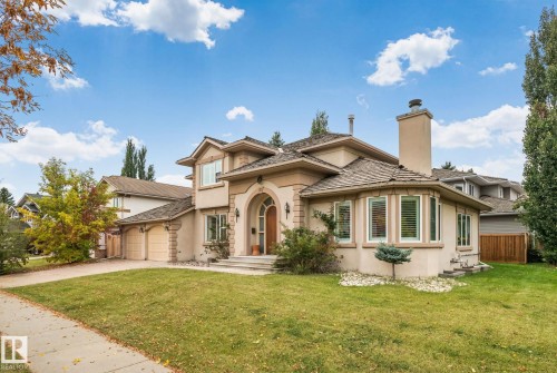 Stucco exterior with stone accents, arched entryway, bay window, prominent chimney, and an attached two-car garage - 10 Eldorado Drive, St. Albert, AB 