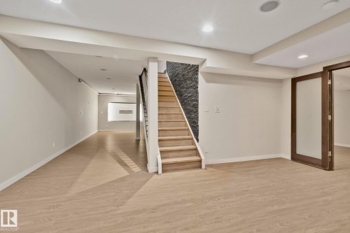 Wood-finish flooring throughout, recessed lighting, and a staircase with a stone-clad wall - 10 Eldorado Drive, St. Albert, AB 