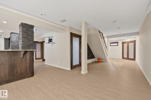 Spacious lower level with wood-finish flooring, recessed lighting, and a built-in bar featuring stone accents and a solid surface countertop - 10 Eldorado Drive, St. Albert, AB 
