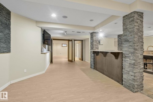 Wood-finish flooring, recessed lighting, stone-clad pillars, built-in bar, and French doors - 10 Eldorado Drive, St. Albert, AB 