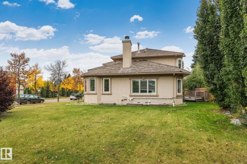 Stucco exterior with a prominent chimney, multiple windows, and a raised wood deck - 10 Eldorado Drive, St. Albert, AB 