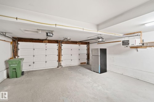 Two overhead garage doors, concrete flooring, overhead lighting, and exposed ceiling utilities - 10 Eldorado Drive, St. Albert, AB 