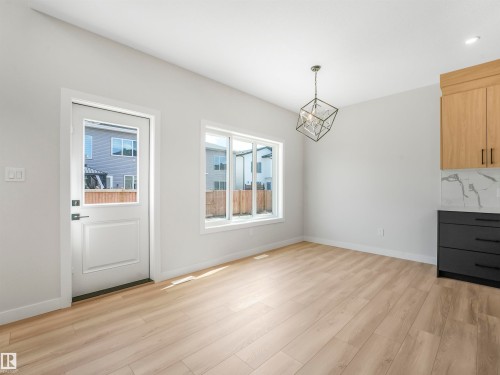 Vaulted ceiling with a geometric chandelier, wood-finish flooring, white walls, and a window with white trim - 11 Dalquist Bay, Leduc, AB 