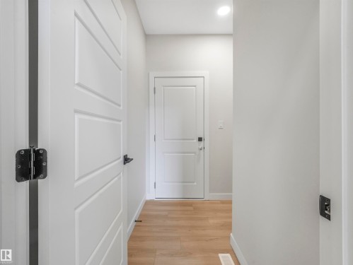 White interior doors with black hardware, recessed ceiling lighting, and wood-finish flooring - 11 Dalquist Bay, Leduc, AB 