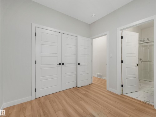 Wood-finish flooring, white paneled doors with black hardware, and an overhead light fixture - 11 Dalquist Bay, Leduc, AB 