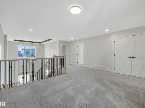 Recessed lighting, wood-finish and wrought iron railing, light gray carpeting, white paneled doors, and a contemporary flush-mount ceiling light - 11 Dalquist Bay, Leduc, AB 