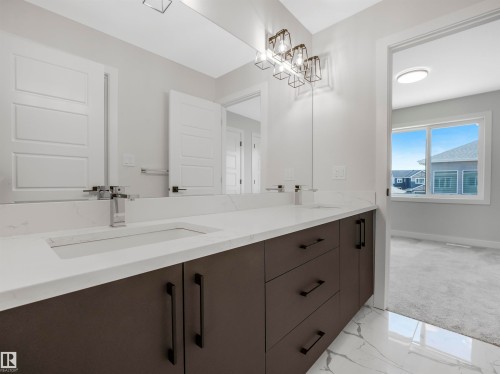 Dual vanity with integrated sinks, white countertop, dark wood-finish cabinetry, and contemporary lighting - 11 Dalquist Bay, Leduc, AB 
