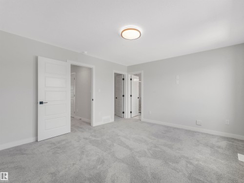 Expansive room featuring plush grey carpeting, light-toned walls, and a modern ceiling fixture - 11 Dalquist Bay, Leduc, AB 