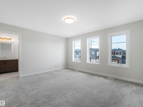 Expansive room featuring three windows, a flush-mount ceiling light fixture, and plush carpet flooring - 11 Dalquist Bay, Leduc, AB 