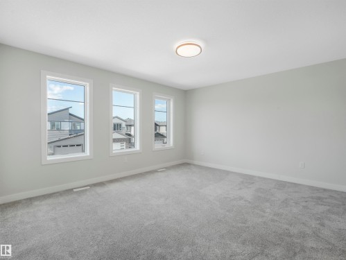 Three large windows, plush grey carpeting, light grey wall paint, and a modern ceiling light fixture - 11 Dalquist Bay, Leduc, AB 