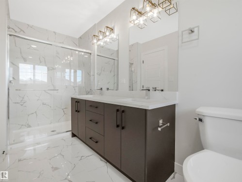 Dual vanity with white countertop, chrome faucets, and dark cabinetry - 11 Dalquist Bay, Leduc, AB 