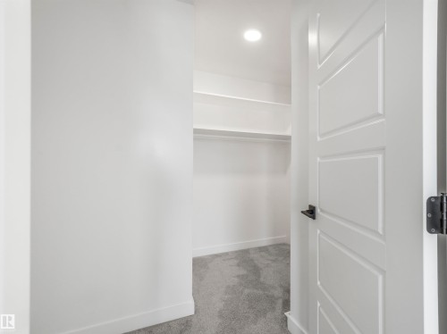 Walk-in closet with built-in shelving, hanging rod, recessed lighting, and grey carpeting - 11 Dalquist Bay, Leduc, AB 