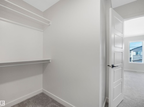 Closet featuring a built-in shelf and hanging rods, with a contemporary paneled door and dark hardware - 11 Dalquist Bay, Leduc, AB 