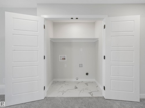 Built-in utility closet with bifold doors, integrated shelving, and a patterned tile floor - 11 Dalquist Bay, Leduc, AB 