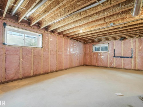 Unfinished basement with concrete flooring, two windows, insulated walls, and exposed ceiling joists - 11 Dalquist Bay, Leduc, AB 