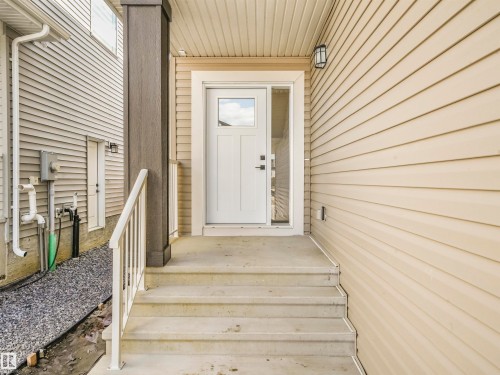 Entryway with concrete steps, white handrail, and a contemporary entry door with sidelite - 11 Dalquist Bay, Leduc, AB 